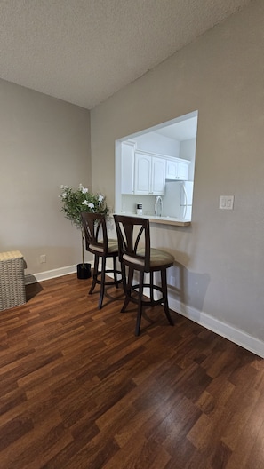 A dining area with a wooden floor, a table with chairs, and a potted plant. - Cozy 2-bedroom apartment 15 minutes away from Disney Parks. FREE PARKING (Kissimmee)