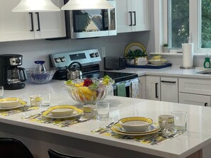 A modern kitchen with white cabinets, stainless steel appliances, and a central island with a fruit bowl. - Amazing Boston Downtown City View Rooms (BOSTON)