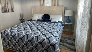 Ein Schlafzimmer mit einem Bett, einer Chandelier, einer Nachttischlampe und einem fensterbelaubten Fenster.