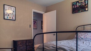 Une chambre à coucher comprenant un lit, une commode, une chaise et une porte donnant sur une autre pièce.