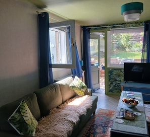 A living room with a sofa, a television, a coffee table with a bowl and a book, and a window with curtains. - Devorgilla View – Bright & Spacious 2-Bed Apartment (Dumfries and Galloway)