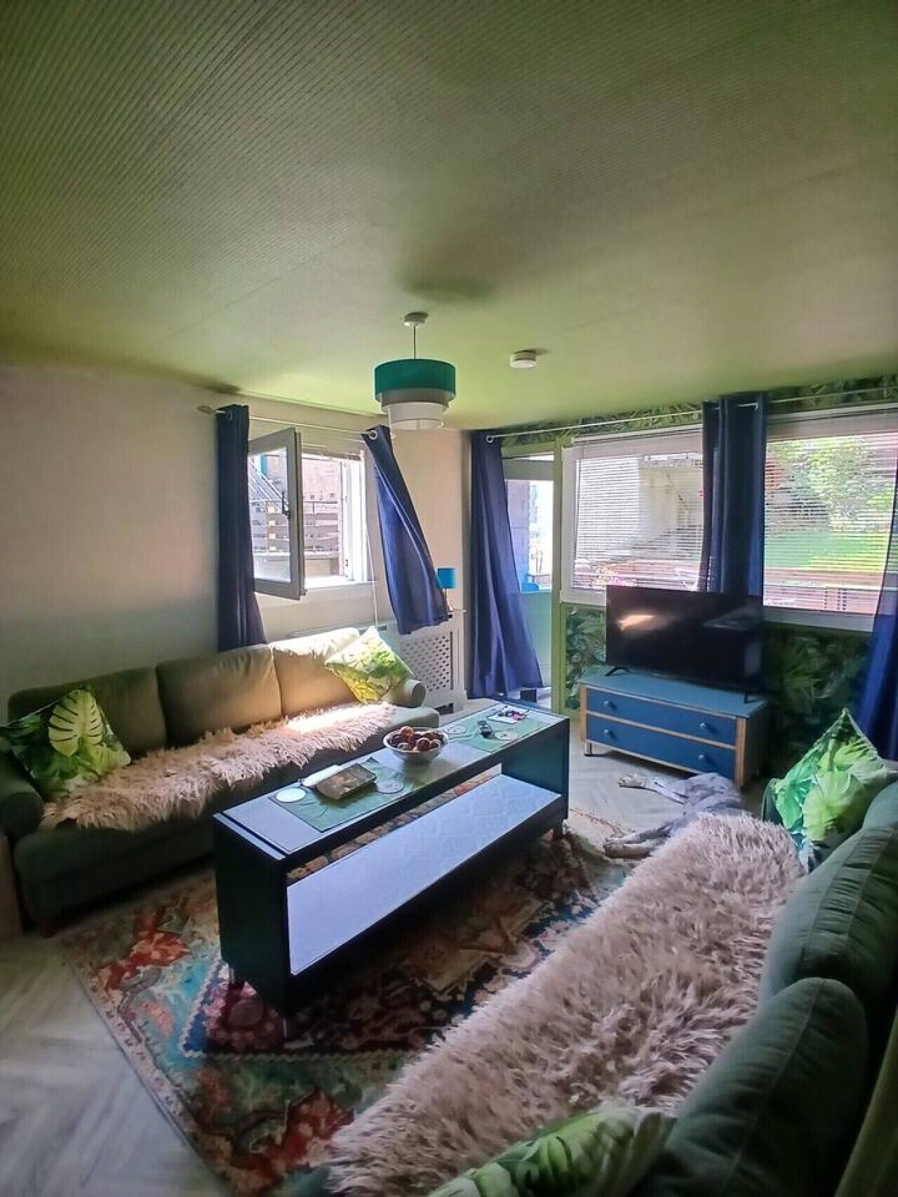 A living room with a sofa, a coffee table, a television, and a patterned rug.