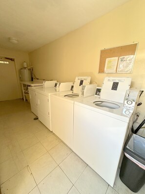 A laundry room with a washing machine, dryer, and a bulletin board on the wall.