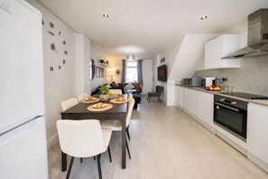 Eine moderne Küche mit Essbereich, weißen Schränken und einem eingebauten Backofen.