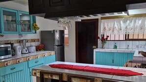 A kitchen with a dining table, cabinets, a refrigerator, and a sink. - Peace and Nature House. (La Fortuna)