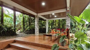 A covered outdoor area with a stone staircase leading to a seating area surrounded by tropical plants. - Peace and Nature House. (La Fortuna)