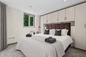 Quarto moderno com uma cama grande, janela com vista para o verde e armários embutidos.