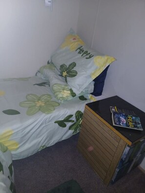 A small, single-bed room with a floral bedspread and a nightstand with a book. - Peacock Lodge Quirky & Tranquil Home Away from Home (Perth and Kinross)