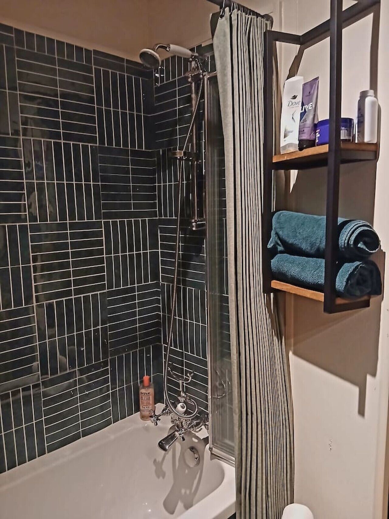 A bathroom with a shower, a sink, and a shelf with toiletries.