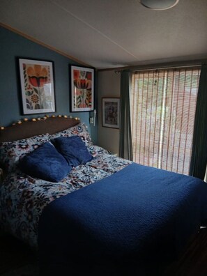 A bed with a floral-patterned headboard, a blue bedspread, and two pillows.