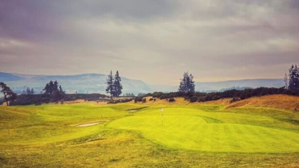 Golfkenttä, jossa on harjoitusviheriö, hiekkabunkkereita ja puita.