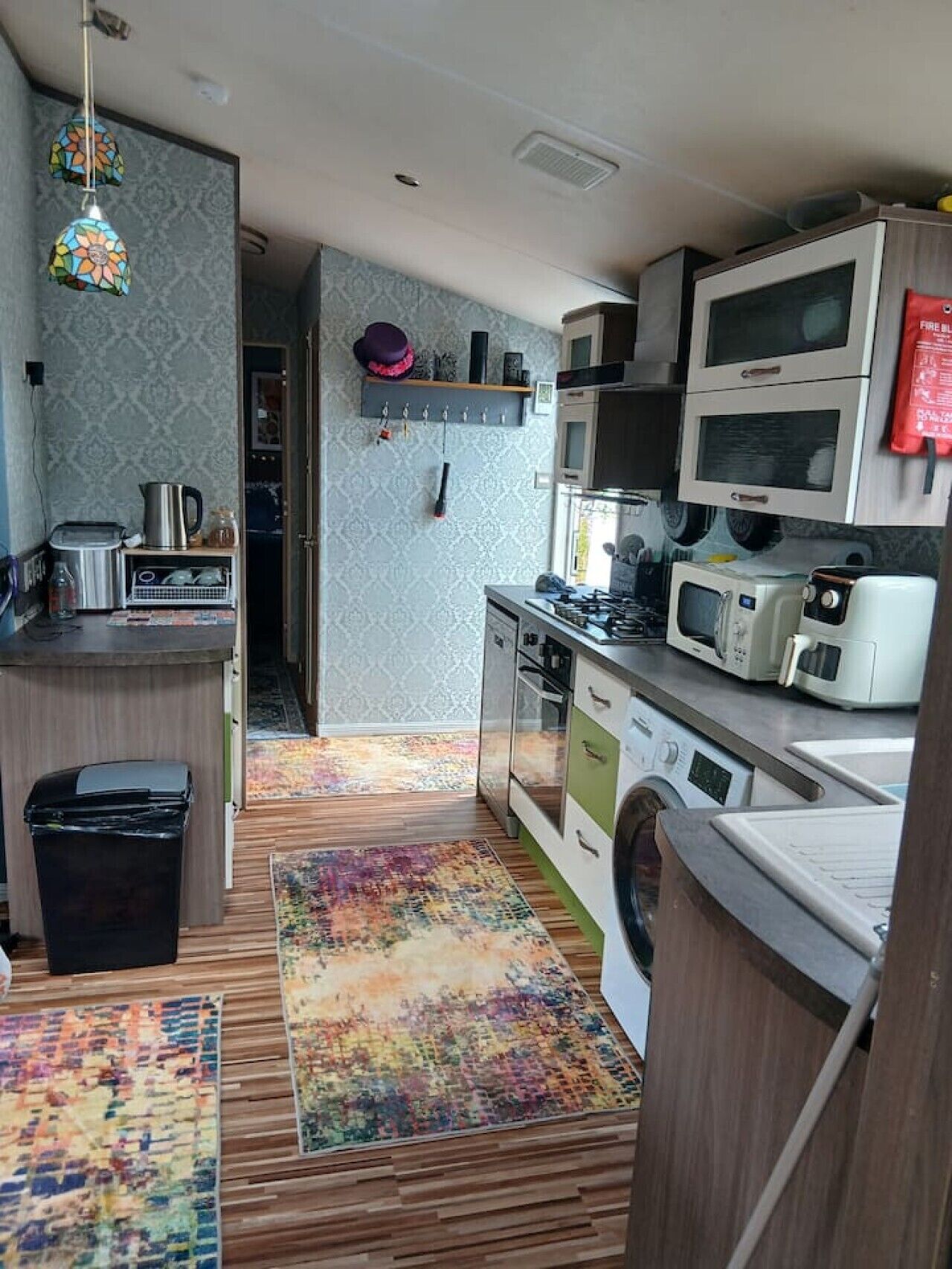 A compact kitchen with a washing machine, microwave, and stove.