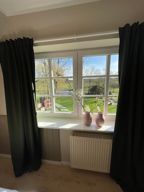 A room with a large window, a radiator, and two vases on the windowsill.