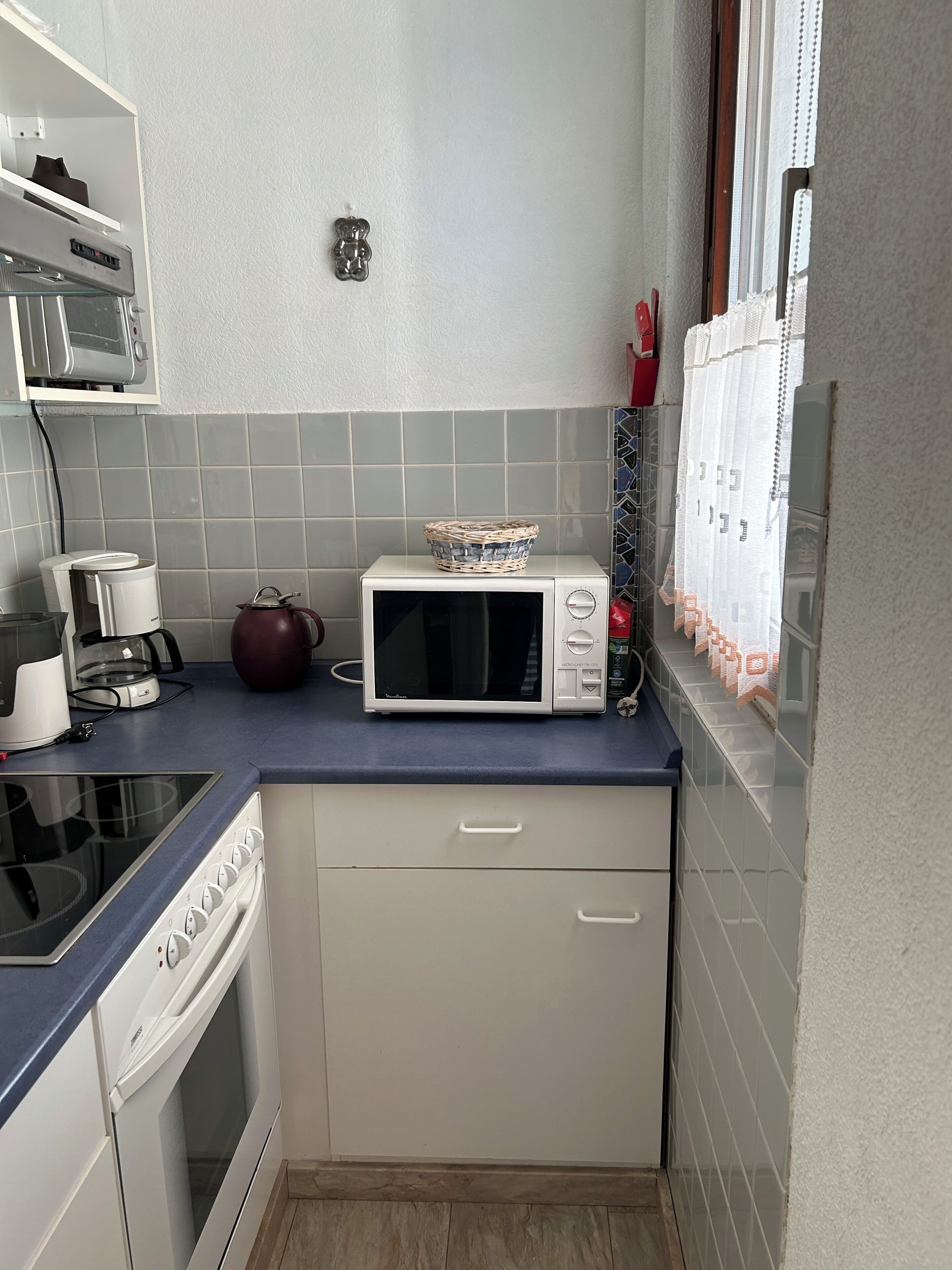 A compact kitchen with a microwave, kettle, and a small oven.