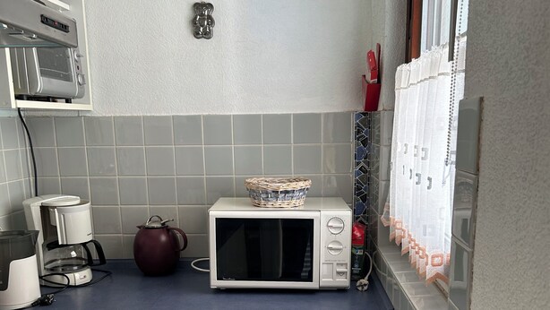 Kompakti keittiö, jossa on mikroaaltouuni, vedenkeitin ja pieni uuni.
