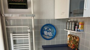 Kompakti keittiö, jossa on sisäänrakennettu uuni, pesuallas ja pieni työtaso.