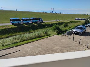 A paved area with a grassy hill and a parked car. - Büsum High-Rise, 1st Floor: Right on the dike—Perlebucht is just a stone's throw away (Büsum)