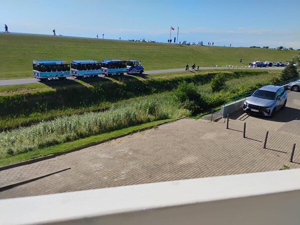 A paved area with a grassy hill and a parked car. - Büsum High-Rise, 1st Floor: Right on the dike—Perlebucht is just a stone's throw away (Büsum)
