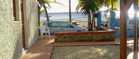 Une propriété située en bord de mer, dotée d’une terrasse, d’une voiture et de palmiers.