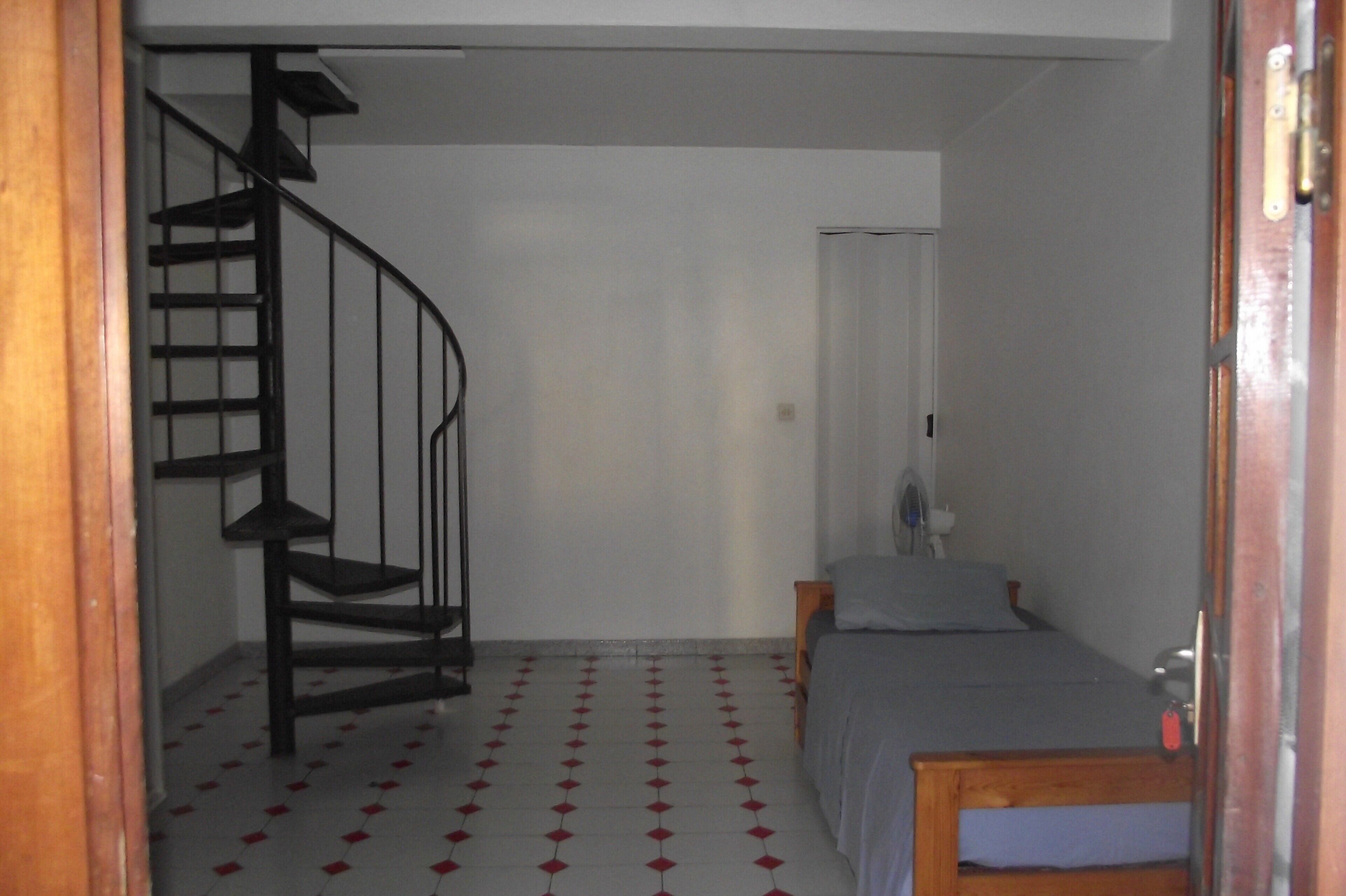 A room with a spiral staircase, a bed, and a small table.