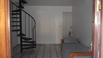 A room with a spiral staircase, a bed, and a small table.