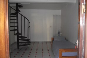 Una habitación con una escalera espiral, una cama y una pequeña mesa.