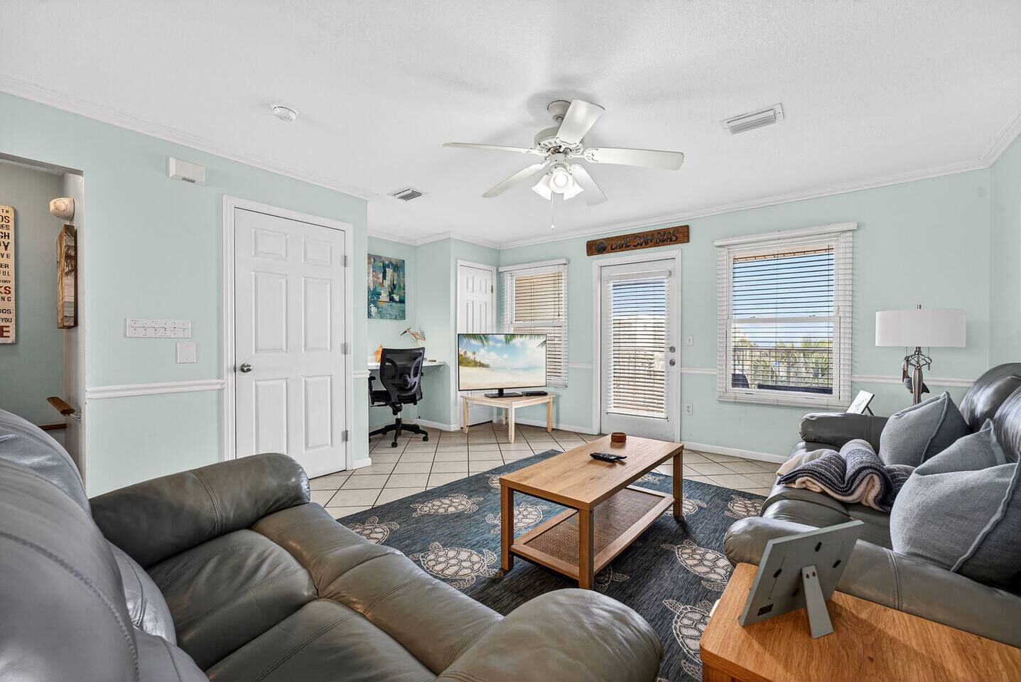 A living room with a sofa, a coffee table, a TV, and a ceiling fan.