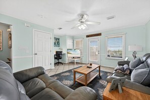 A living room with a sofa, a coffee table, a TV, and a ceiling fan.