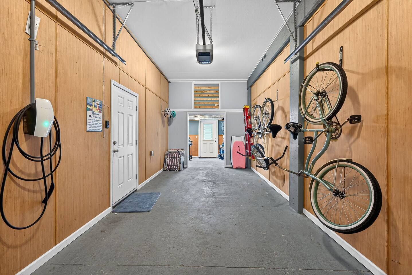 Un couloir aux murs en bois, un projecteur fixé au plafond et des vélos accrochés au mur.