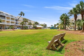 A hotel courtyard with a grassy lawn, palm trees, and a playground.