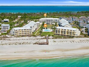 A beachfront hotel with multiple buildings, a swimming pool, and a beach area.