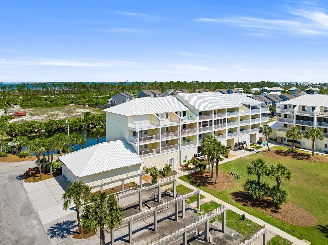 A multi-story hotel with a pool, surrounded by palm trees and a clear view of the ocean.
