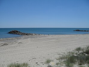 Ein Strand mit blauem Himmel, ruhiger See und Felsen.
