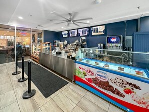 Een horecagebied met een toonbank, menuborden en een vitrine voor ijs.
