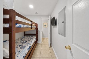 A bunk bed with patterned bedding, a door with a brass handle, and a television mounted on the wall. - High Tide Hideaway at Shores of Panama #1918 - Oceanfront, High-Rise, Pools, Covered Parking (Panama City Beach)