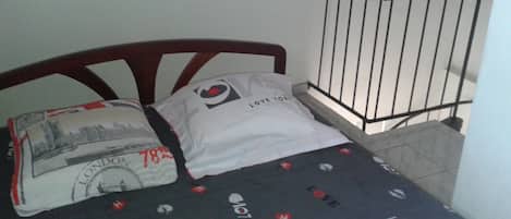 A bed with a black sheet featuring 'LOVE' and 'LONDON' prints, a pillow with a 'LONDON' print, and a white pillow with 'LOVE FOR ALL' text.