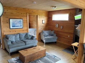 Ein gemütliches Blockhäuschen-Interieur mit zwei Sofas, einer Holzkiste und einem Kamin.