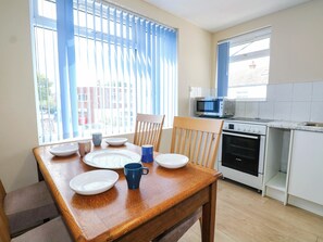 A kitchen with a dining table, chairs, a microwave, and an oven. - 90 A Station Road (New Milton)