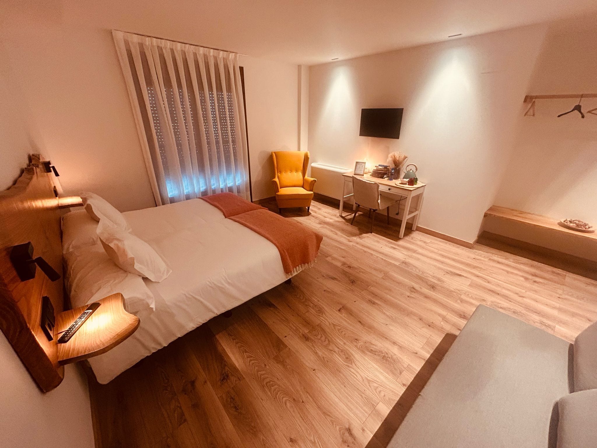 Une chambre d’hôtel équipée d’un lit, d’une table de chevet, d’une lampe, d’une chaise, d’un bureau et d’un téléviseur fixé au mur.
