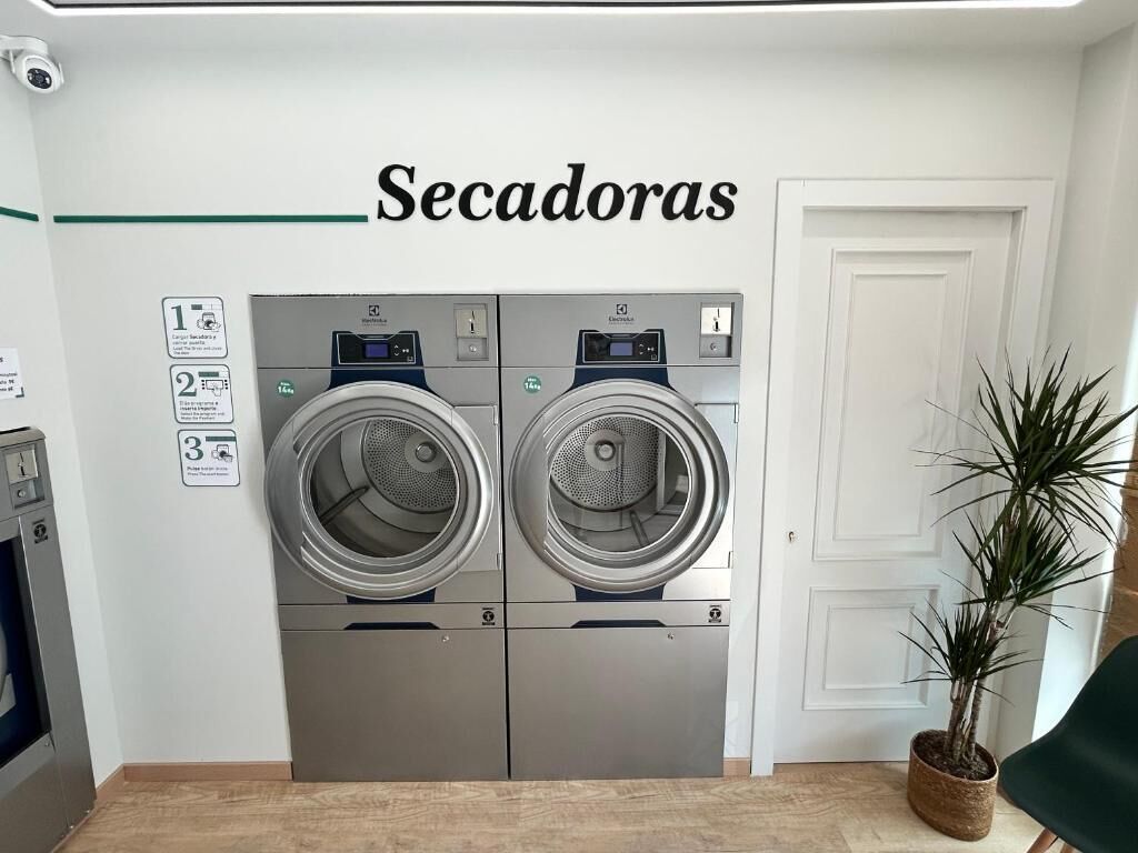 Une buanderie équipée de deux machines à laver et d’un panneau indiquant le nombre de machines disponibles.