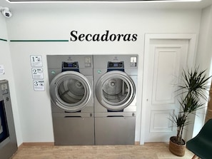 Zona de lavandería con dos lavadoras y un cartel que indica la cantidad de máquinas disponibles.