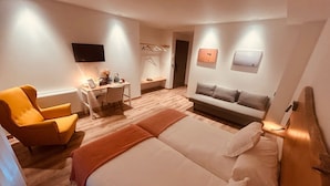 A hotel room with a bed, a sofa, a desk, and a chair.