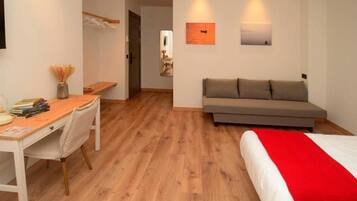Een kamer met een bed, een bank, een bureau en een stoel. Twee wandlampen en een schilderij aan de muur.