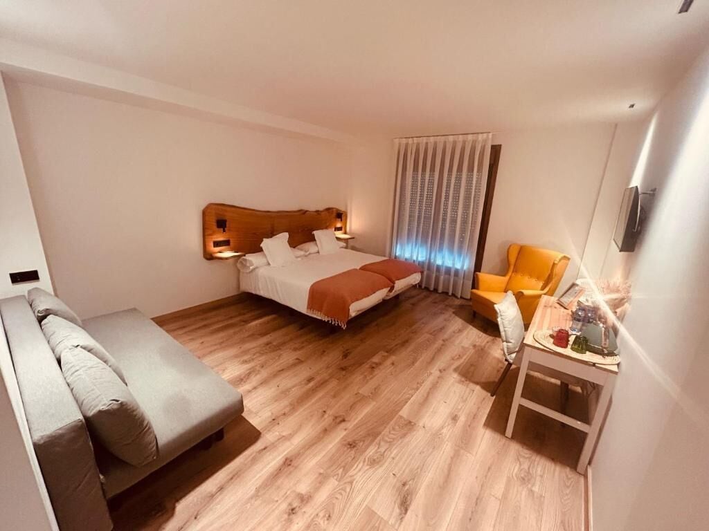 Een hotelkamer met een bed, een bank, een stoel en een kleine tafel met een lamp.