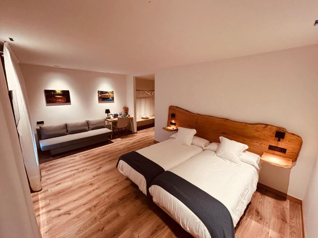 A bedroom with a large bed, a sofa, and a small table with a lamp.