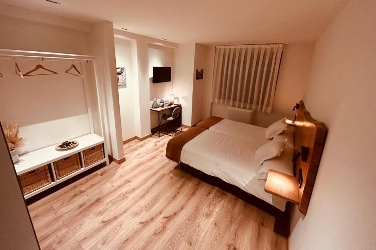A hotel room with a bed, bedside table, and a desk with a chair.