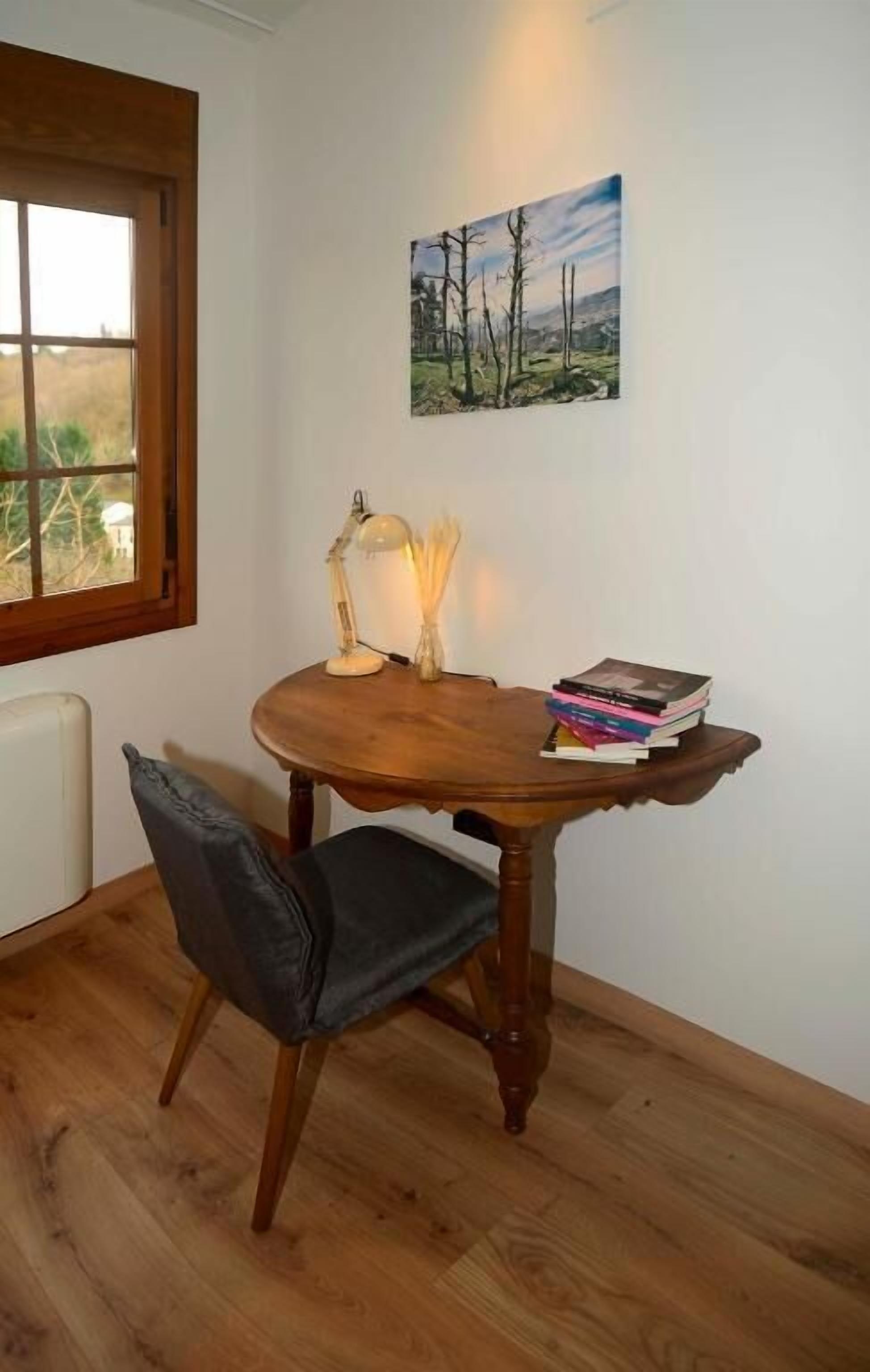 A wooden dining table with a chair, a lamp, and a stack of books.