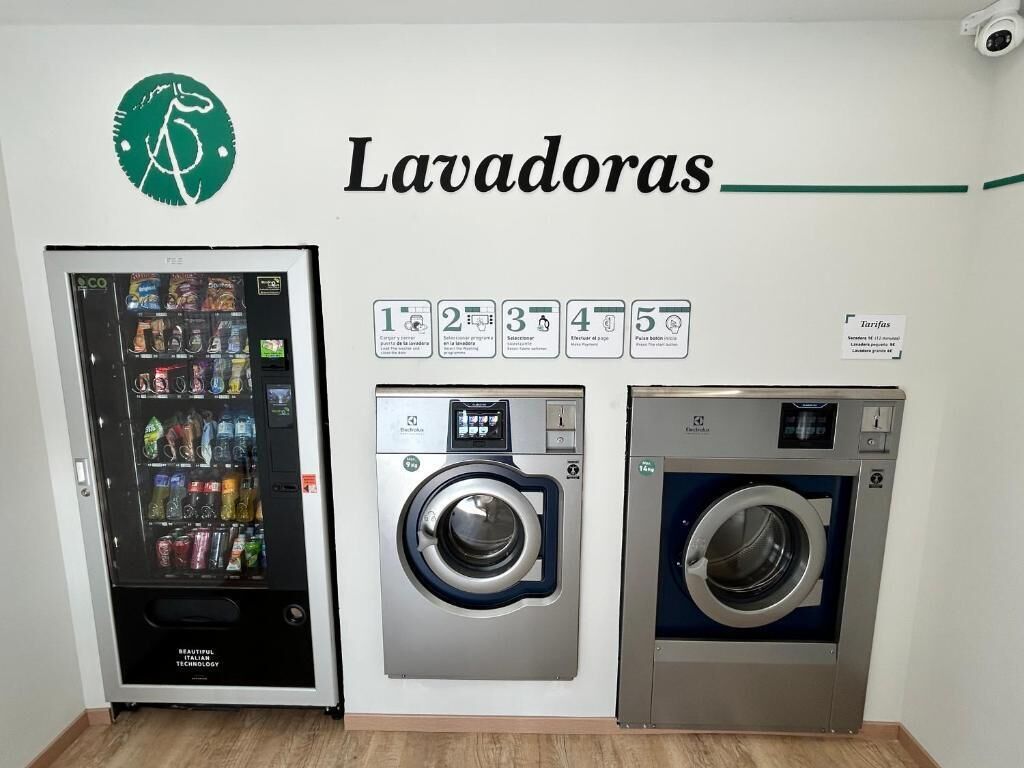 Una lavandería con máquinas expendedoras, lavadoras y secadoras, junto con un cartel que indica la cantidad de máquinas disponibles.