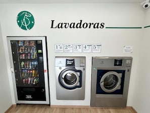 Una lavandería con máquinas expendedoras, lavadoras y secadoras, junto con un cartel que indica la cantidad de máquinas disponibles.