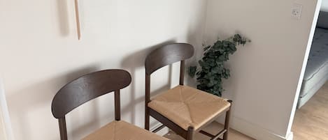 Two wooden chairs with woven seats and backs, positioned against a wall with a coat rack above.